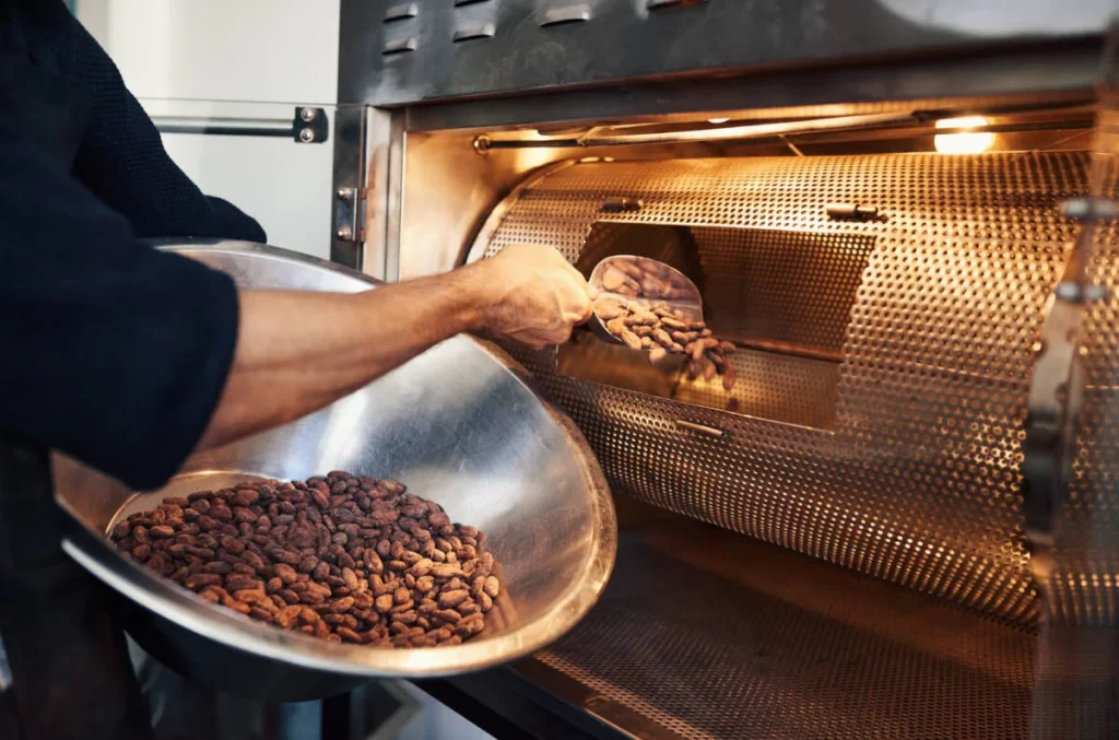 PEssoa torrando sementes de cacau em forno