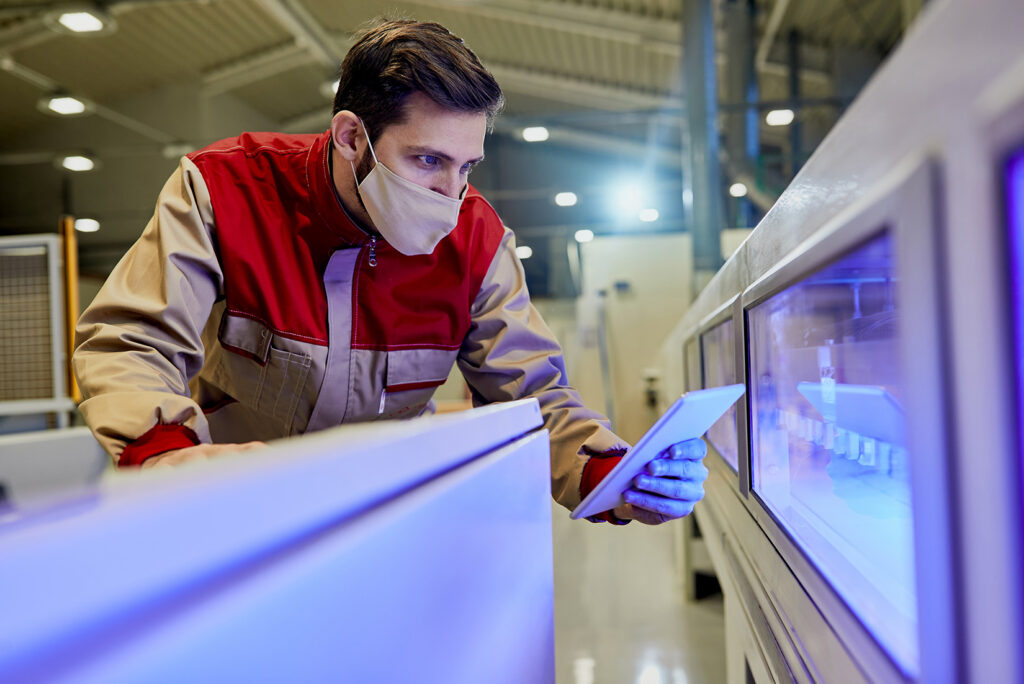 Homem de blusa vermelha checando máquina industrial